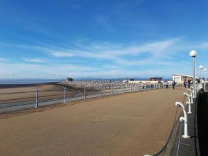 a road next to a beach with a fence at Morecambes wise place in Morecambe