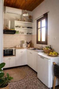 a kitchen with white cabinets and a sink and a window at Hakuna Matata in Skala Eresou