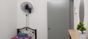 a room with a fan on a wall and a chair at arin syah homestay in Jasin