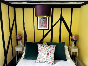 a bedroom with a bed with a black and yellow wall at Romantic Boutique Cottage with pink roll-top bath-Hastings Old Town in Hastings