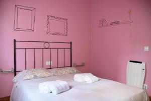 a bedroom with pink walls and a bed with towels at Ciudad Rodrigo La Casa Azul in Ciudad-Rodrigo