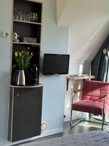 a living room with a tv and a red chair at Hotelhuisjes Oosterleek in Oosterleek