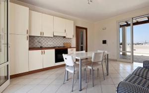 レウカにあるCasa del Sole by BarbarHouseの白いキャビネット、テーブルと椅子付きのキッチンが備わります。