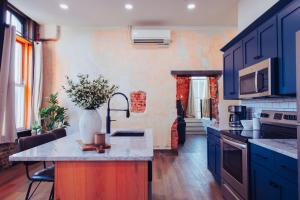 a kitchen with blue cabinets and a vase of flowers on a counter at American Hall - Kaufman Suite in Millersburg