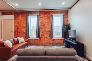 a living room with a couch and a brick wall at American Hall - Hamilton Suite in Millersburg