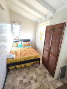 a small bedroom with a bed and a window at Mage B&B 1 in Roseau