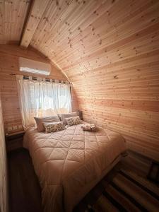 a bedroom with a large bed in a wooden room at Casa Leandro glamping wooden tiny house in Lachi
