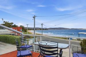 a balcony with chairs and a table and a view of the water at Beachfront Beauty Bellerive in Bellerive