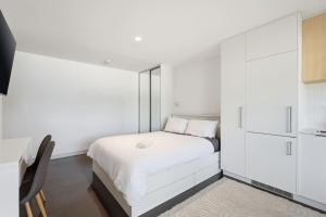 a bedroom with a white bed and white cabinets at Modern Beachside Studio in Kingston Beach