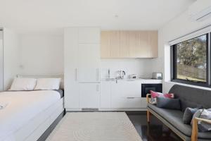 a white room with a bed and a couch at Modern Beachside Studio in Kingston Beach