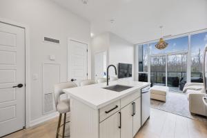 eine weiße Küche mit Spüle und ein Wohnzimmer in der Unterkunft Lake Simcoe Stays - Friday Harbour's Official Rental Program - Aspen Suite in Innisfil