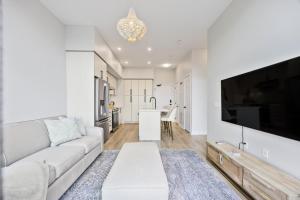 ein Wohnzimmer mit einem weißen Sofa und einem Fernseher in der Unterkunft Lake Simcoe Stays - Friday Harbour's Official Rental Program - Aspen Suite in Innisfil + 1 Foto
