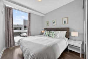 a white bedroom with a large bed and a window at Lake Simcoe Stays - Friday Harbour's Official Rental Program - Scyamore Suite in Innisfil