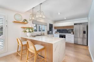 a kitchen with white cabinets and a large island with chairs at Coastal Waterfront Broadbeach Waters in Gold Coast