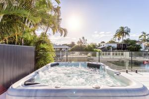 a jacuzzi tub on a patio with palm trees at Coastal Waterfront Broadbeach Waters in Gold Coast