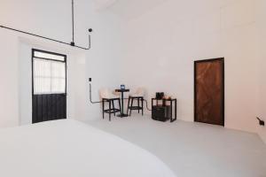 a white room with a table and chairs and a door at Cocoon Oaxaca City- Curated Stay In Oaxaca Centro in Oaxaca City