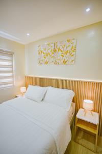 a bedroom with a bed and two night stands with two lamps at Silid Pahingahan at Forest Residences in Antipolo