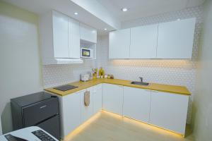 a kitchen with white cabinets and a black refrigerator at Silid Pahingahan at Forest Residences in Antipolo +19 photos