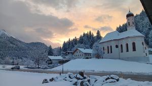a church covered in snow in front of a mountain at Ferienwohnung Landliebe in Pinswang