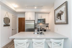 eine Küche mit einer großen weißen Theke und weißen Stühlen in der Unterkunft Lake Simcoe Stays - Friday Harbour's Official Rental Program - Tamarack Suite in Innisfil