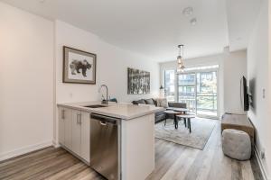 eine Wohnungsküche mit Spüle und ein Wohnzimmer in der Unterkunft Lake Simcoe Stays - Friday Harbour's Official Rental Program - Tamarack Suite in Innisfil
