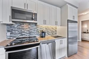 Eine Küche mit weißen Schränken und Edelstahlgeräten in der Unterkunft Lake Simcoe Stays - Friday Harbour's Official Rental Program - Walnut Suite in Innisfil