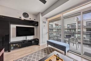 ein Wohnzimmer mit Fernseher und großem Fenster in der Unterkunft Lake Simcoe Stays - Friday Harbour's Official Rental Program - Walnut Suite in Innisfil