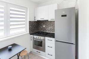 a kitchen with white cabinets and a refrigerator and a table at Nicolle Prestige Apartment in Piteşti
