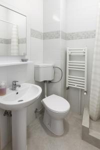 a white bathroom with a toilet and a sink at Nicolle Prestige Apartment in Piteşti +3 photos