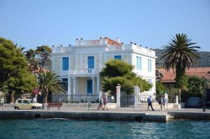 a white building with people walking in front of the water at Metropolis Nextdoor in Vathi