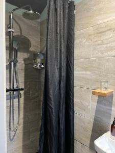 a shower with a black shower curtain in a bathroom at The Aultnamain Shepherds Hut in Wester Fearn