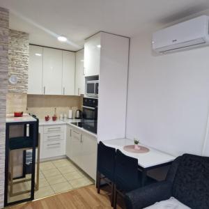 a kitchen with white cabinets and a table and chairs at Apartman Zivkovic in Bosanska Dubica