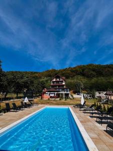 a pool with chairs and a house in the background at PENSIUNEA SUBCETATE in Polovragi