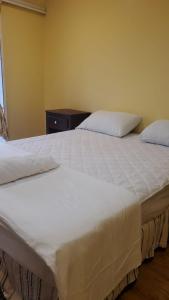 a bedroom with two beds with white sheets at Casona Blanca Guesthouse in Chinandega