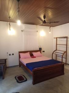a bedroom with a bed with pink and blue sheets at Miu Villa in Ahangama