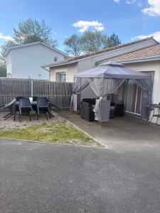 a patio with a tent and tables and chairs at Maison entière avec jardin , Proche Bordeaux, Rocade et Arkéa Arena in Bouliac