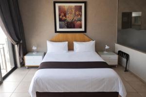 a bedroom with a large bed and a painting on the wall at Europrime Hotels Airport in Boksburg +19 photos
