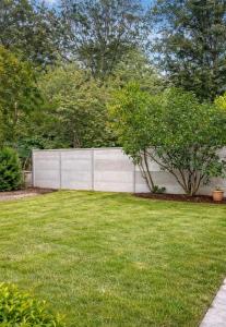a fence in front of a yard with grass at Maison prairie en fleurs in Le Perray-en-Yvelines +2 photos