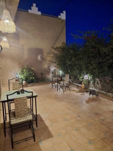 a patio with tables and chairs and a dog walking around at Dar Dallali maison d'hôtes et excursions in Mhamid +72 photos