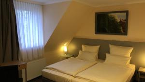 a bedroom with a bed with white pillows and a window at Löns Hotel Garni in Garbsen