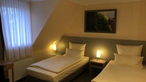 two beds in a small room with two lamps at Löns Hotel Garni in Garbsen