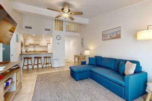 a living room with a blue couch and a kitchen at Sand Dollar E201 in Pensacola Beach