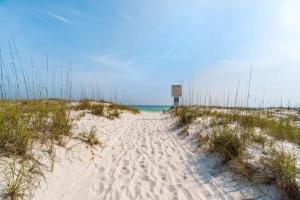 a beach with a sign in the sand and the ocean at Sand Dollar E201 in Pensacola Beach