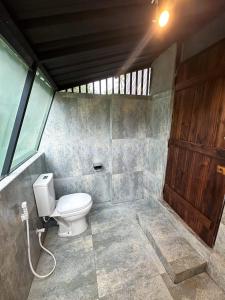 a bathroom with a toilet and a wooden door at Alpine Heights in Kumburuteniwela +4 photos