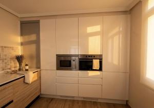 a kitchen with white cabinets and a microwave at BILBAO ENEA - Apartamento 2 habitaciones cerca de San Mamés in Bilbao