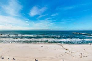 a beach with people standing on the sand and the ocean at Calypso 906W in Panama City Beach