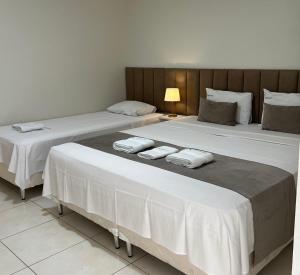 two beds in a hotel room with white sheets at Rio Hotel in Petrolândia
