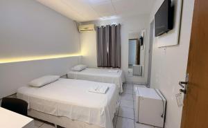a room with two beds and a flat screen tv at Rio Hotel in Petrolândia