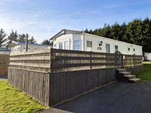 a wooden fence with a house behind it at Dornoch Holiday Chalet in Proncy +7 photos