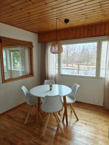 a dining room with a white table and chairs at Kodikas talo lammen rannalla in Raahe